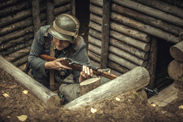 A soldier of the Finnish army during world war II, in a trench with a rifle, wearing a helmet on his head