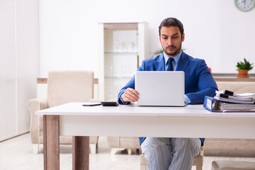 Young male employee working from house in self-isolation concept