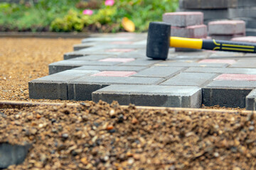 Laying gray concrete paving slabs in the courtyard of the house on a sandy foundation. Selective focus. - Powered by Adobe