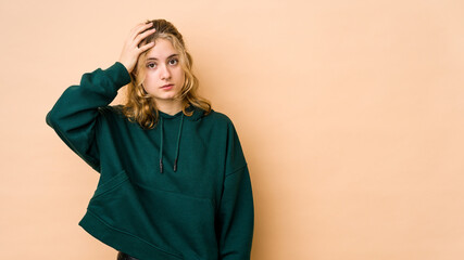 Young caucasian woman isolated on beige background being shocked, she has remembered important meeting.