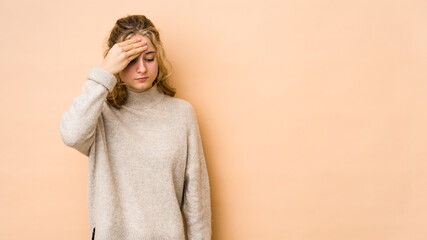 Young caucasian woman isolated on beige background having a head ache, touching front of the face.