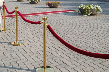Gold plated rope barrier with red event carpet