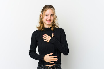 Young caucasian woman on white backrgound laughs happily and has fun keeping hands on stomach.