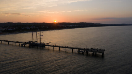 Fototapeta na wymiar Segelschiff an Seebrücke im Sonnenuntergang