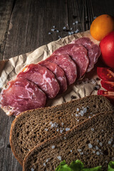 Sliced jerky on a board. Vegetables, bread and meat on the table.