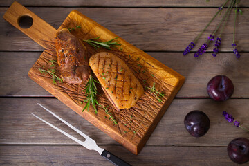 Roast duck breast fillet on serving board. Overhead horizontal image