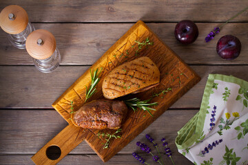 Roast duck breast fillet on serving board. Overhead horizontal image