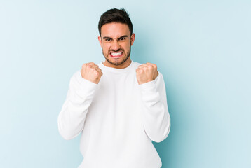 Young caucasian man isolated on blue background upset screaming with tense hands.