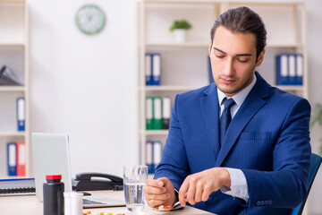 Young male employee and a lot of pills on the desk