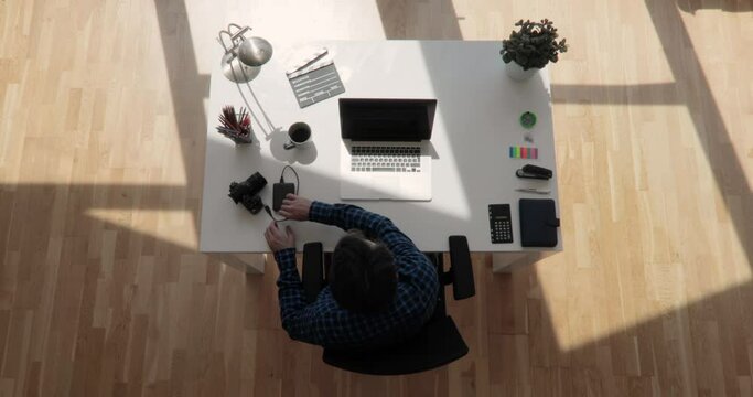 Top view shot of a filmmaker transfers data to a usb hard disk with floating sun shot in 4k