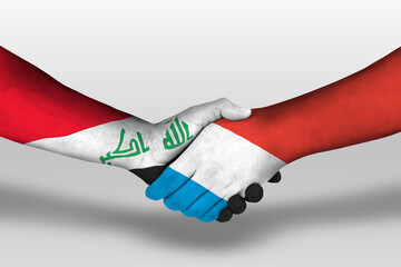 Handshake between luxembourg and iraq flags painted on hands, illustration with clipping path.