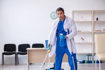 Young male contractor disinfecting clinic in pandemic concept