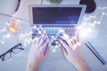 Double exposure of man's hands typing over laptop keyboard and forex chart hologram drawing. Top view. Financial markets concept.