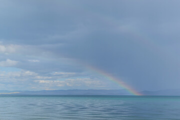 Rainbow over the lake. Baikal. Dry bay. Beautiful blue sky background. Water mirrors water