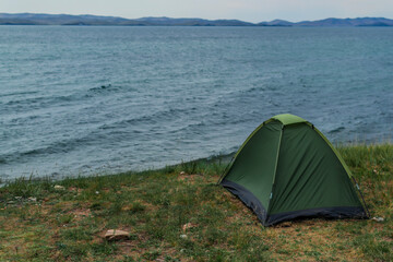 Lakeside tent, baikal in summer, green tent, tourism and travel. Beautiful sky background