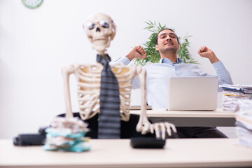 Young male employee and skeleton in the office