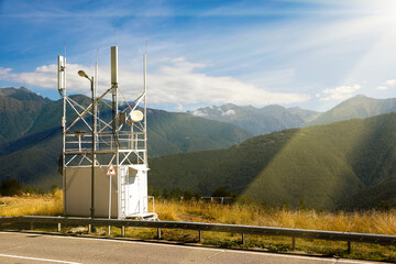 Telecommunications transmitters 4G, 5G. cellular base station with transmitter antennas near a road on the background of mountains.