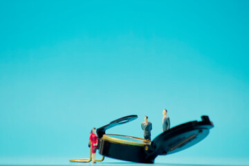 Miniature businessman and compass on blue background