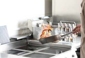 Male chef cooking tasty food on stove in restaurant