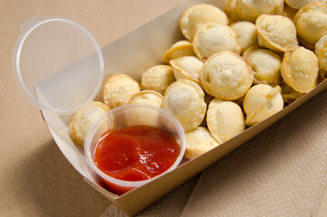 fried dumplings with red sauce in a cardboard box