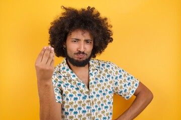 Fototapeta na wymiar Young man with afro hair over wearing hawaiian shirt standing over yellow background angry gesturing typical italian gesture with hand, looking to camera