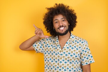 Young man with afro hair over wearing hawaiian shirt standing over yellow background showing up number six Liu with fingers gesture in sign Chinese language