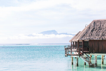 Thatched roof over-water bungalows on a tropical island in the South Pacific ocean