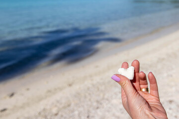 Fototapeta na wymiar Woman holding a heart shaped piece of coral on a sandy tropical beach