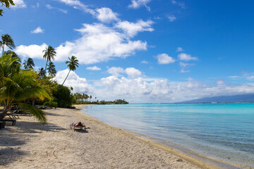 A woman lays in the sun to tan on an exclusive and private beach on a tropical island