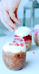 Hand of a woman who is adding fruit chips on a dessert