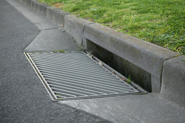 Gutter of a stormwater drainage system in perspective on the side of an road with markings. Australia. Melbourne. 