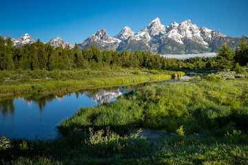 Fototapeta na wymiar Schwabachers Landing in the early morning in Grand Teton National Park, with mountain reflections on the water creek