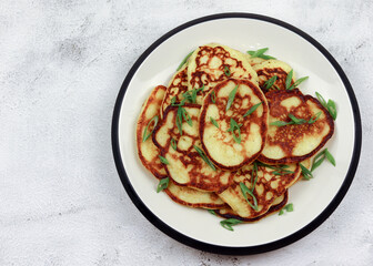 Potato pancakes on a round plate on a light gray background. Top view, flat lay
