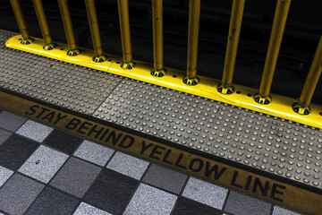 Fototapeta premium Stay behind the yellow line. Metro warning markings and yellow safety poles on the metro platform. The subway platform.