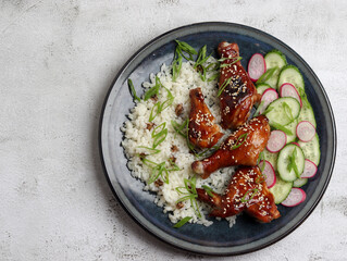 Teriyaki chicken with rice on a round plate on a light gray background. Top view, flat lay