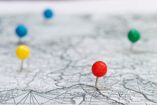 Close up white and black map with colorful stickpins pinpointing a location © julie