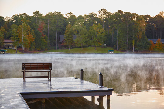 Bench on the dock of the bay on a Georgia lake with steam rising from the water