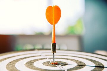 Bullseye or dart board has red dart arrow throw hitting the center of a shooting target for...