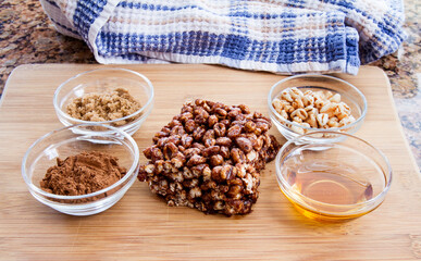 Large puffed wheat square treat with small glass bowls of raw ingredients beside; delicious and chewy puffed wheat squares