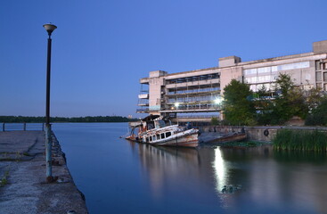 Naklejka premium half-submerged old boat at the pier of an abandoned river station