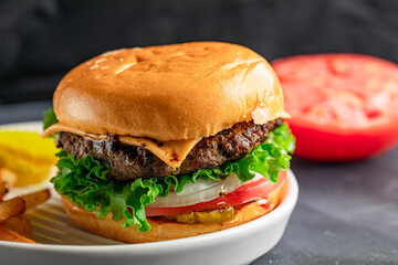 Delicious juicy and spicy burger with slice of tomato, onion, and cheese. Served with fries and pickles.