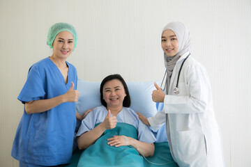 Asian female doctors and his female patient with thump up in bed at hospital