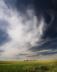Fototapeta na wymiar Dramatic cloudy sky over a farm field in the prairies of Rocky View County Alberta Canada.
