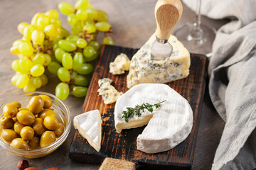 Cheese Brie and Dorblu or Gorgonzola on a board with grapes and olives. Italian food antipasti
