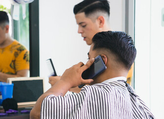 client uses his cell phone while getting a haircut at a barbershop