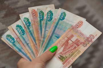 Сlose up of woman hand with bundle of money Russian Banknotes of one thousand and five tousand rubles. Business, finance, saving, banking and people concept