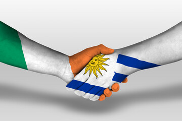 Handshake between uruguay and ireland flags painted on hands, illustration with clipping path.