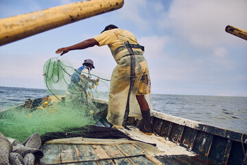 Pescadores preparando las redes de pesca en un bote en medio del océano pacifico