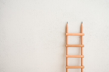 Minimal creative concept in business, finance and education learning. Ladder made from simple wooden pencils with white wall background copy space. Planning growth step by step for success goal. © pla2na