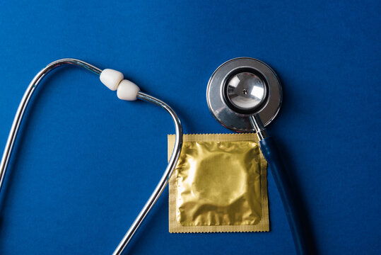 World sexual health or Aids day, Top view flat lay medical equipment, condom in pack and stethoscope, studio shot isolated on dark blue background, Safe sex and reproductive health concept - Powered by Adobe